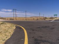 the paved road is painted yellow and black in the desert area, surrounded by power lines