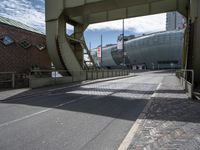 a paved road leading to an arena under construction with stairs at the top of the street