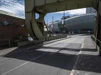 a paved road leading to an arena under construction with stairs at the top of the street