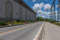 the road is paved and empty near buildings and wires and poles are all present at this time