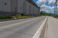 the road is paved and empty near buildings and wires and poles are all present at this time