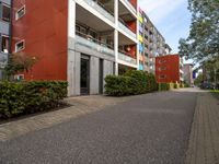 a long paved sidewalk in front of a multi - story building with many windows on each level