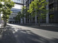 a paved street in the city with a bench in the middle of it and two people walking on both side