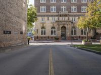 the paved street by the brick building has no traffic on it as well as trees