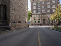 the paved street by the brick building has no traffic on it as well as trees