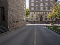 the paved street by the brick building has no traffic on it as well as trees