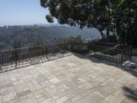 a paved walkway that stretches into the distance, near trees, and hills as well