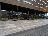 outside dining area with tables and chairs on large pavement walkway outside building with roof and wooden structure