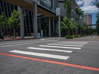 the pedestrian crosswalk and walkway has stripes painted on it's side in front of an office building