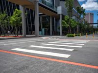 the pedestrian crosswalk and walkway has stripes painted on it's side in front of an office building