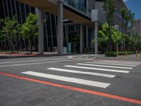 the pedestrian crosswalk and walkway has stripes painted on it's side in front of an office building