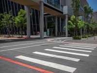 the pedestrian crosswalk and walkway has stripes painted on it's side in front of an office building