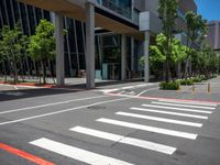 the pedestrian crosswalk and walkway has stripes painted on it's side in front of an office building