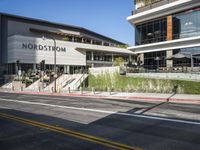 pedestrians are walking along a street outside an outdoor retail store or store building with the name nordstrom in front