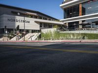 pedestrians are walking along a street outside an outdoor retail store or store building with the name nordstrom in front