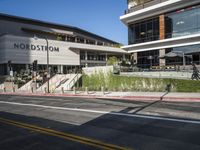 pedestrians are walking along a street outside an outdoor retail store or store building with the name nordstrom in front