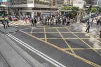 people are crossing the street at an intersection with a tram going down it's side
