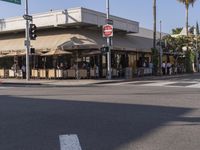 people are sitting outside of a cafe in the day time, on the corner and in front of the street