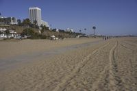 a group of people on a beach next to the ocean and a resort on the horizon