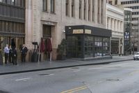 people standing outside of a bar on a city street while another man sits at the counter