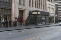 people standing outside of a bar on a city street while another man sits at the counter