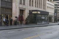 people standing outside of a bar on a city street while another man sits at the counter