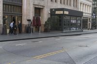 people standing outside of a bar on a city street while another man sits at the counter