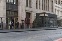 people standing outside of a bar on a city street while another man sits at the counter