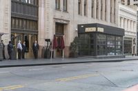 people standing outside of a bar on a city street while another man sits at the counter