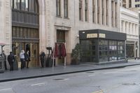 people standing outside of a bar on a city street while another man sits at the counter