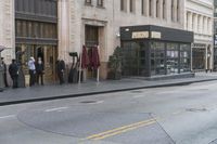 people standing outside of a bar on a city street while another man sits at the counter