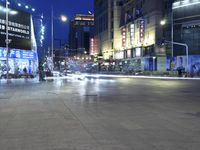 people walking across an empty sidewalk in a city at night time on a street corner