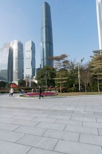 a group of people are walking around in the city on a sunny day with skyscrapers in the background