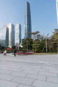 a group of people are walking around in the city on a sunny day with skyscrapers in the background