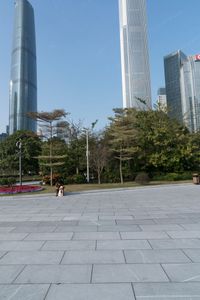 a group of people are walking around in the city on a sunny day with skyscrapers in the background