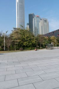 a group of people are walking around in the city on a sunny day with skyscrapers in the background