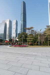 a group of people are walking around in the city on a sunny day with skyscrapers in the background