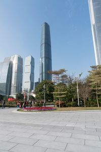 a group of people are walking around in the city on a sunny day with skyscrapers in the background