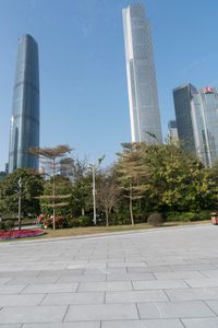 a group of people are walking around in the city on a sunny day with skyscrapers in the background