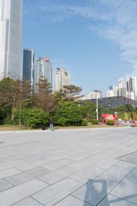 a group of people are walking around in the city on a sunny day with skyscrapers in the background