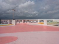 people walking and jogging across a large concrete plaza under cloudy skies with pink and yellow accents