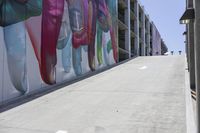 people walking down a side walk near a large building that has a giant mural on it