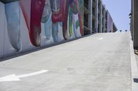 people walking down a side walk near a large building that has a giant mural on it