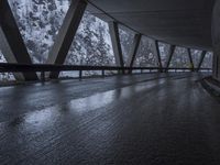 people walk under an overpass in the rain on a mountaintop road with snow