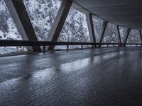 people walk under an overpass in the rain on a mountaintop road with snow