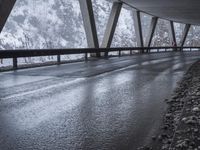 people walk under an overpass in the rain on a mountaintop road with snow