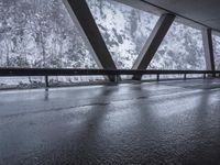 people walk under an overpass in the rain on a mountaintop road with snow