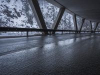 people walk under an overpass in the rain on a mountaintop road with snow