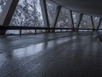 people walk under an overpass in the rain on a mountaintop road with snow