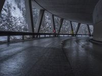 people walk under an overpass in the rain on a mountaintop road with snow